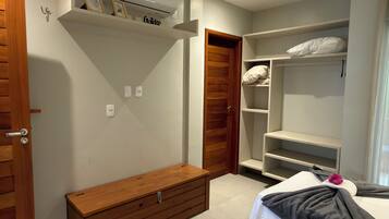 Habitación de hotel con cama, banco de madera, armario y aire acondicionado integrado.