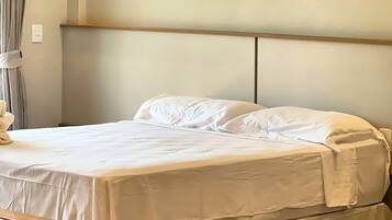 A bed with a wooden headboard, a white bedspread, and a bedside table with a light switch.
