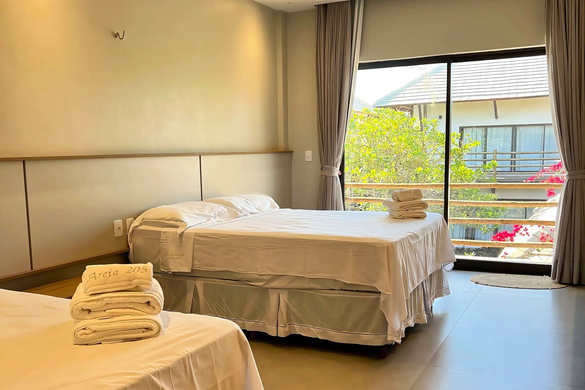 Habitación de hotel con dos camas, un ventanal con cortinas y vistas al exterior.