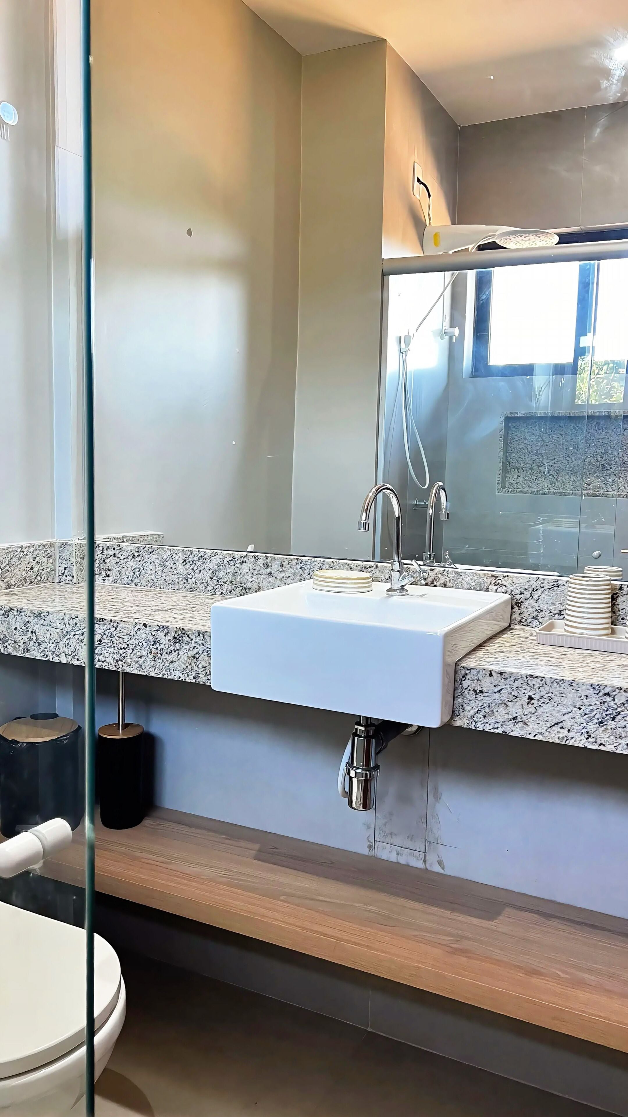 Een badkamer met een wit wastafel, een spiegel en een douche.