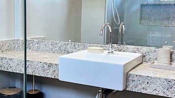 Een badkamer met een wit wastafel, een spiegel en een douche.