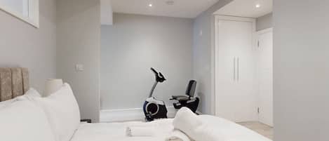 Habitación de hotel moderna con cama, bicicleta estática y puerta que da a un baño.