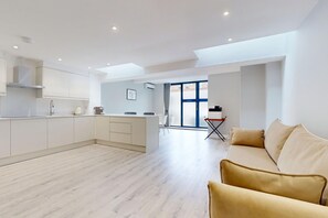 A modern apartment with a kitchen, a dining area, and a living room with a sofa. - Tidy 1BR Flat w/Parking & Aircon Near River Thames (London)