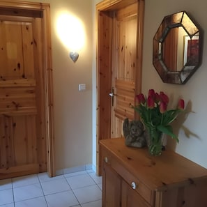 A wooden interior with a wall-mounted light, a mirror, and a vase with flowers.