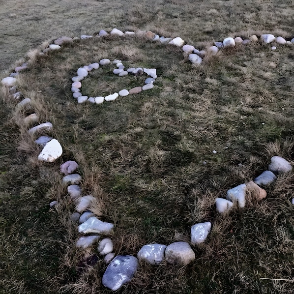 A heart-shaped arrangement of stones on a grassy field.