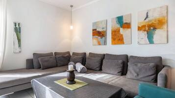A modern living room with a sofa, a table with a candle, and abstract wall art.