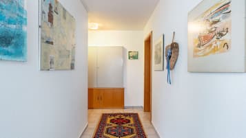 Ein Flur mit Teppichmuster, Holztüren und verschiedenen Kunstwerken an den Wänden.