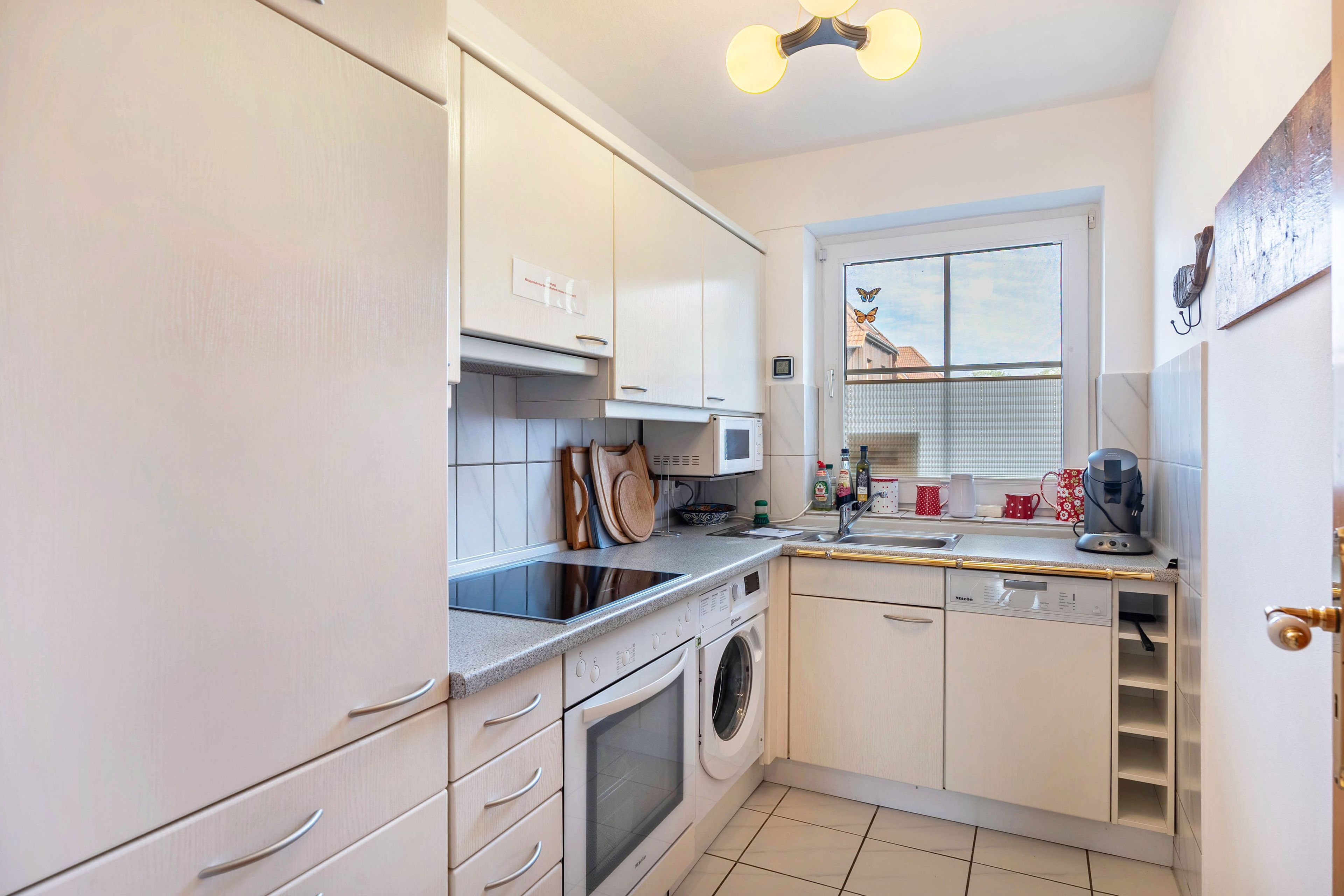A compact kitchen with a built-in oven, microwave, and a washing machine.