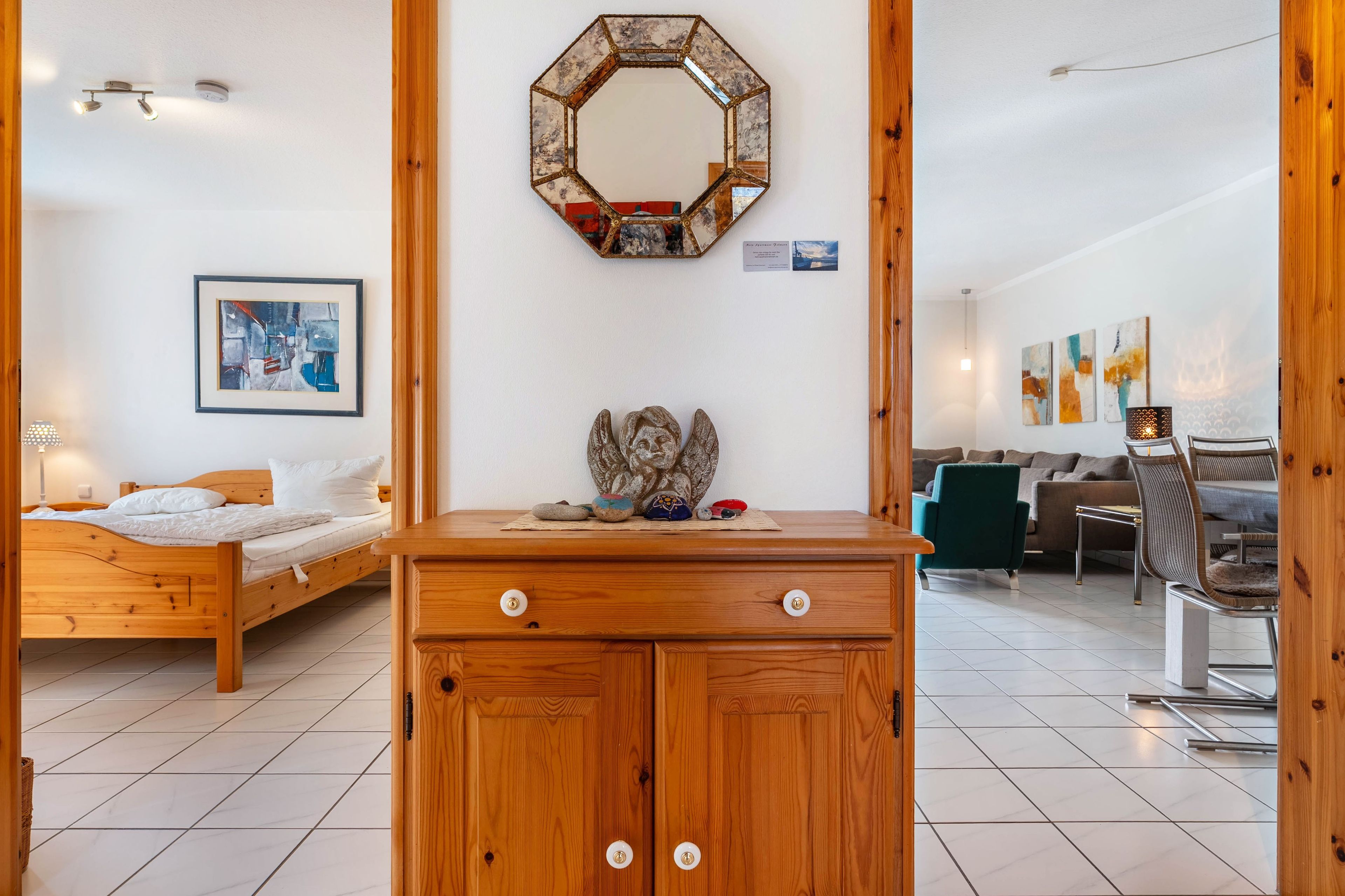 Een slaapkamer met een houten bed, een dressoir, een spiegel en een ingelijst kunstwerk aan de muur.