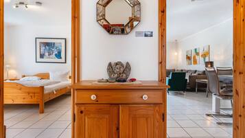 Een slaapkamer met een houten bed, een dressoir, een spiegel en een ingelijst kunstwerk aan de muur.