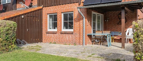 A brick house with a patio, a table, and chairs.