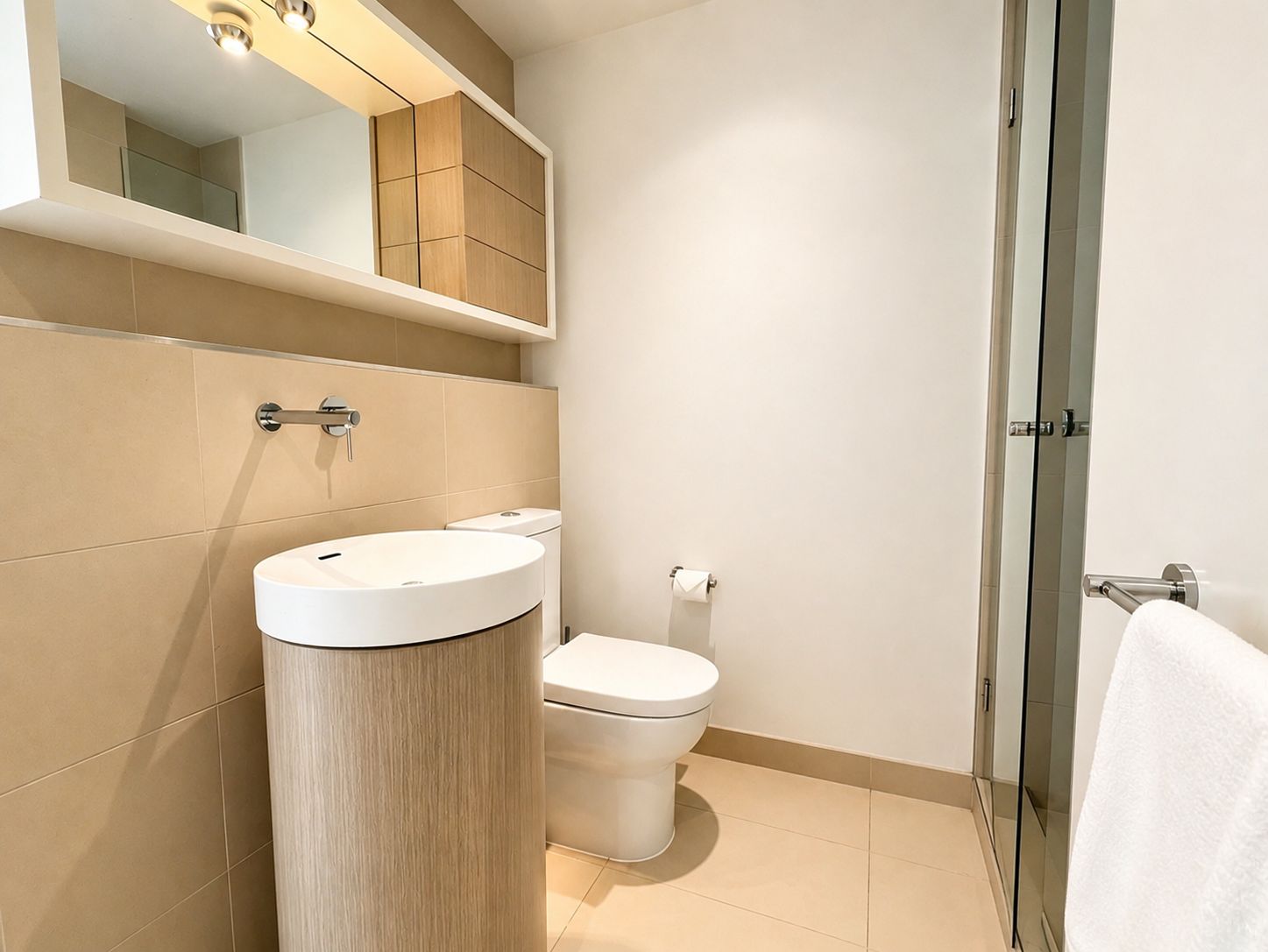 A modern bathroom with a sink, toilet, and glass shower enclosure.