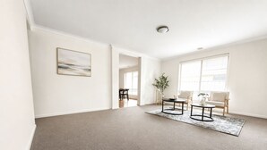 Sala de estar espaçosa, com cores neutras, uma janela ampla e design minimalista.