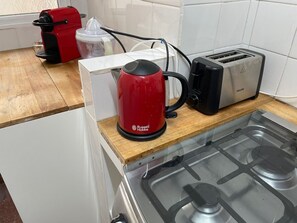 A kitchen with a gas stove, a red Russell Hobbs kettle, a toaster, and a red electric kettle. - Los Arcos Palermo Palace (Buenos Aires)