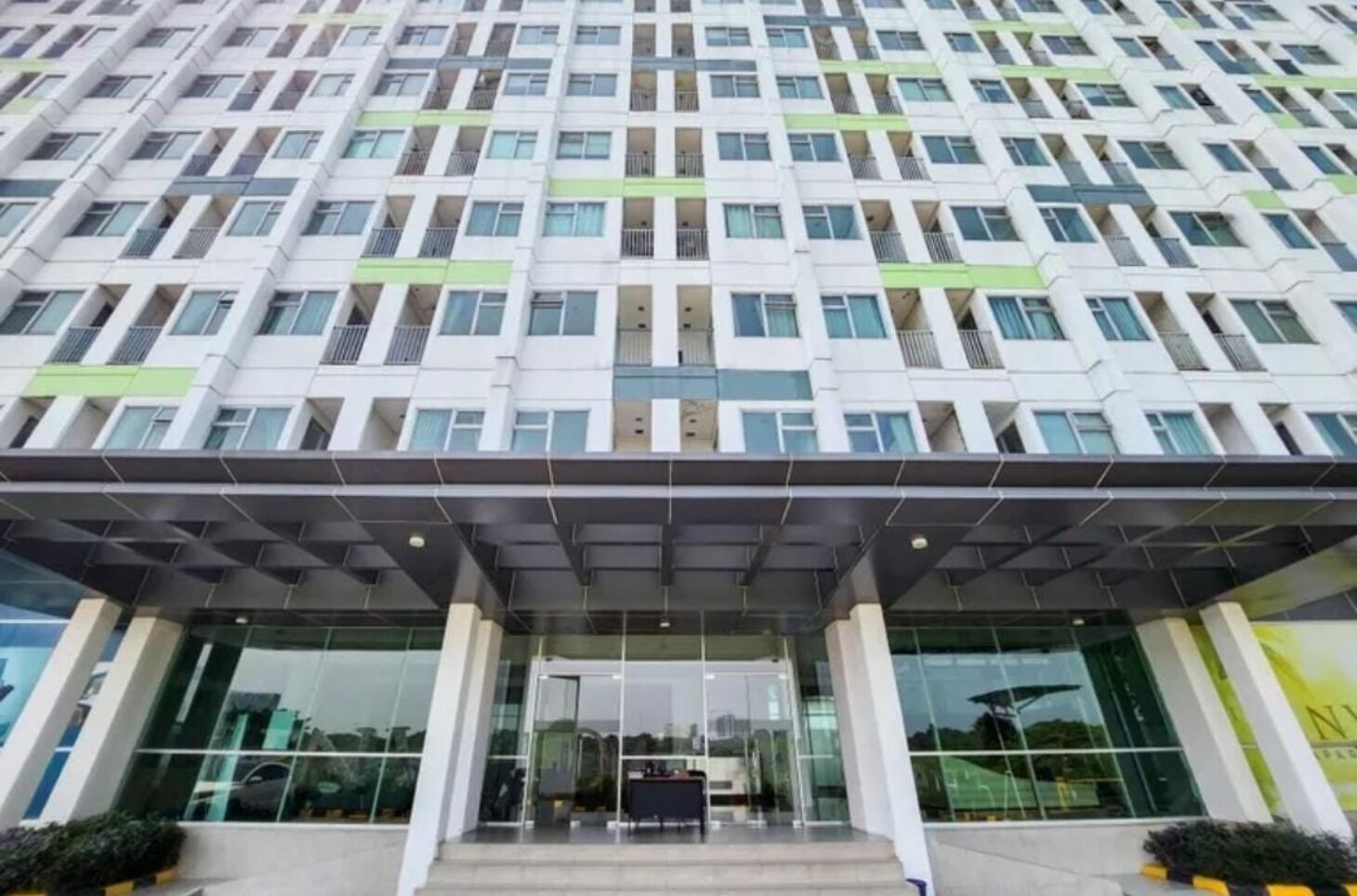 A modern multi-story building with a glass entrance and a covered area in front.
