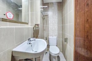 Et badeværelse med en hvid vask, toilet og bruseområde.
