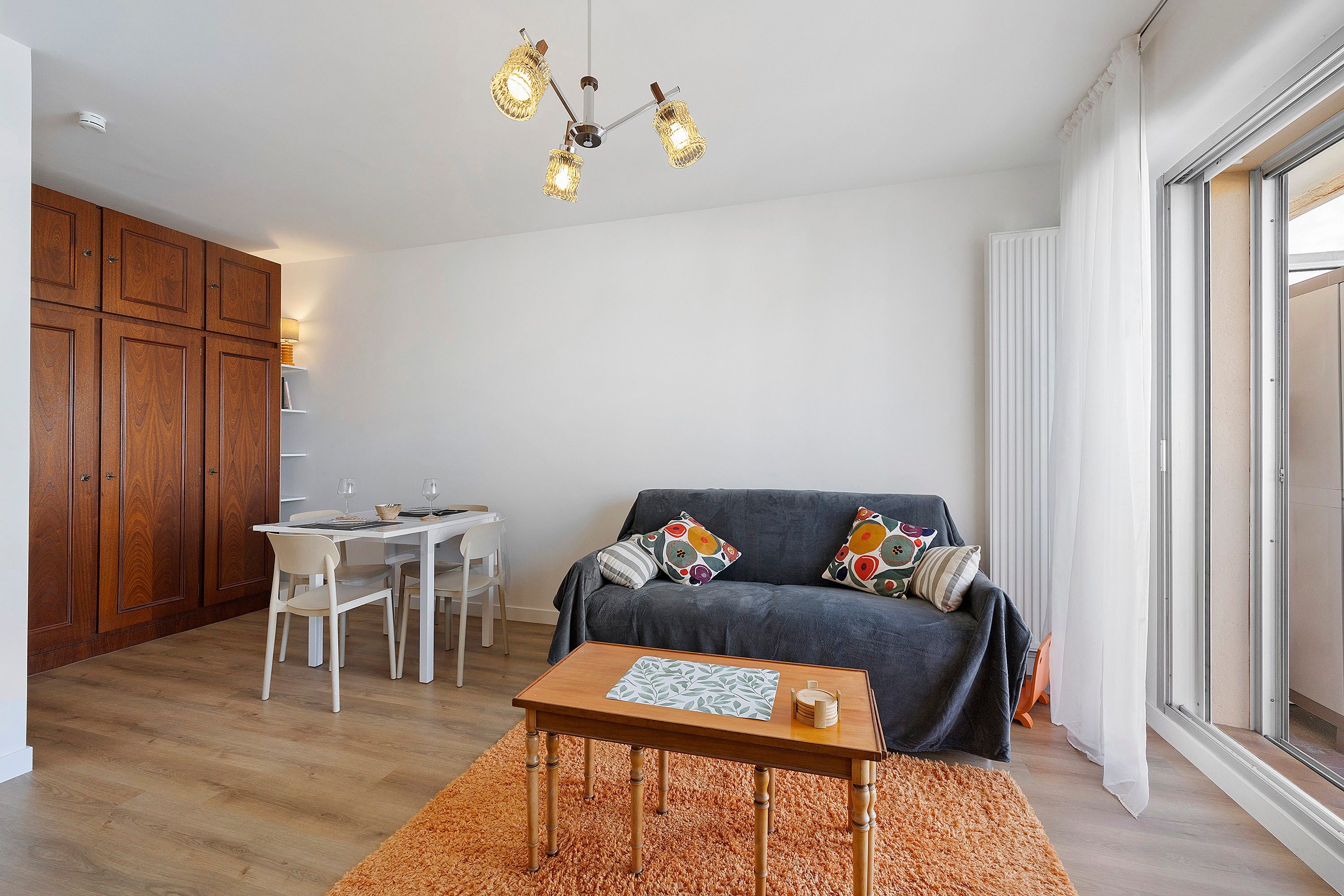 A modern living room with a grey sofa, wooden dining table, and a small wooden coffee table.