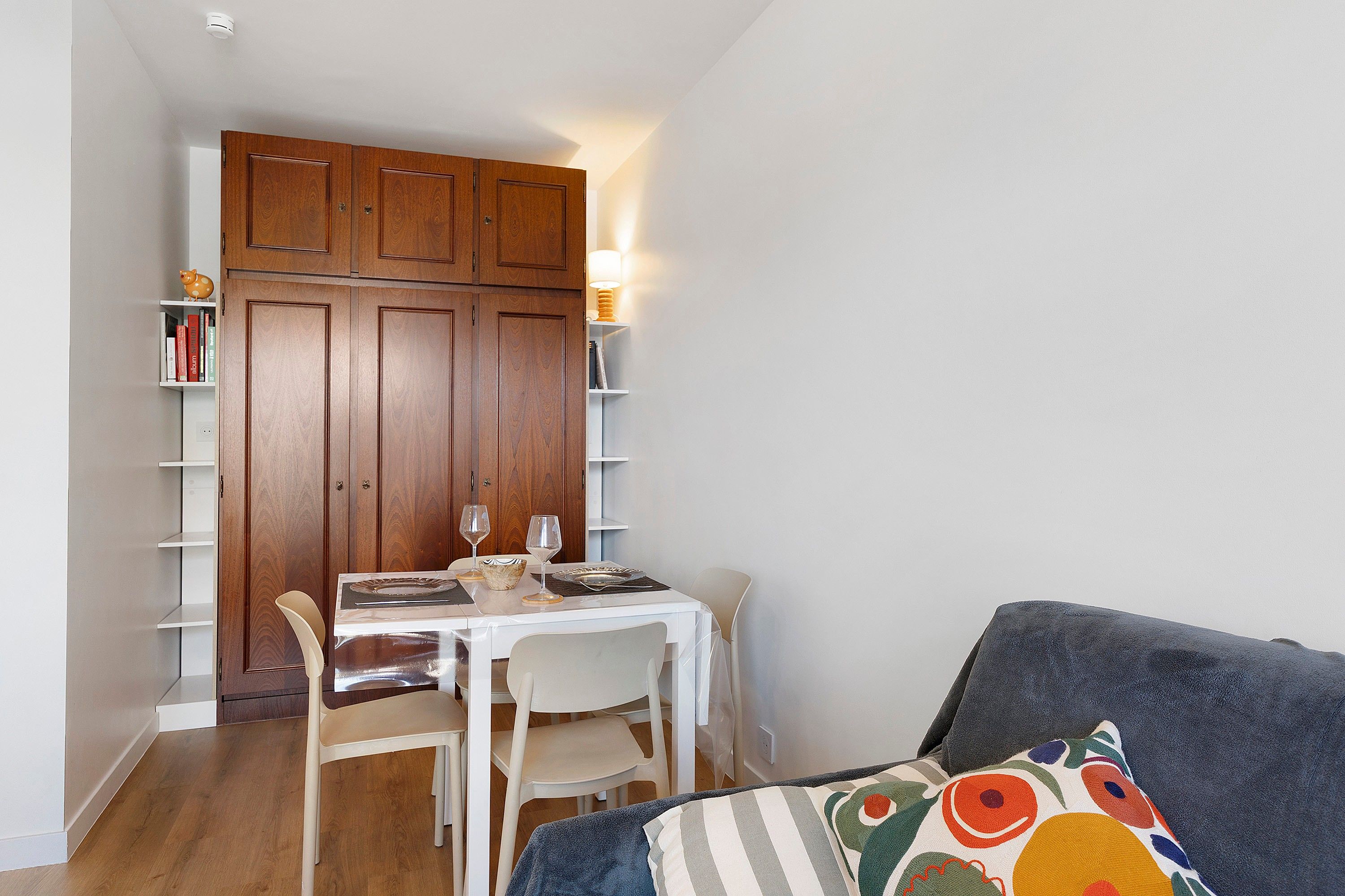 Un espace de vie compact comprenant un coin repas, un canapé et une bibliothèque.