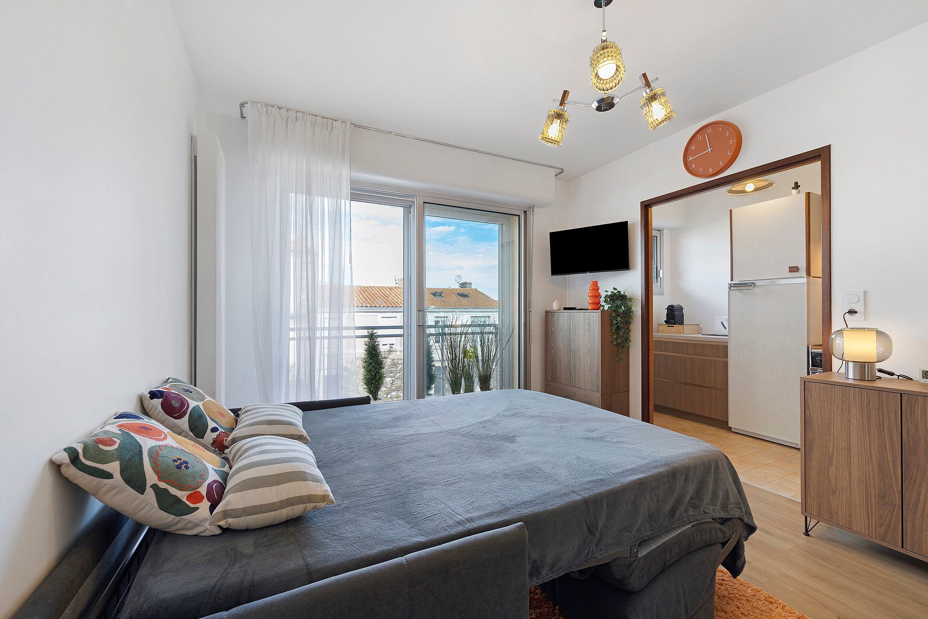 Une chambre avec un lit, une télévision, un miroir et un balcon.