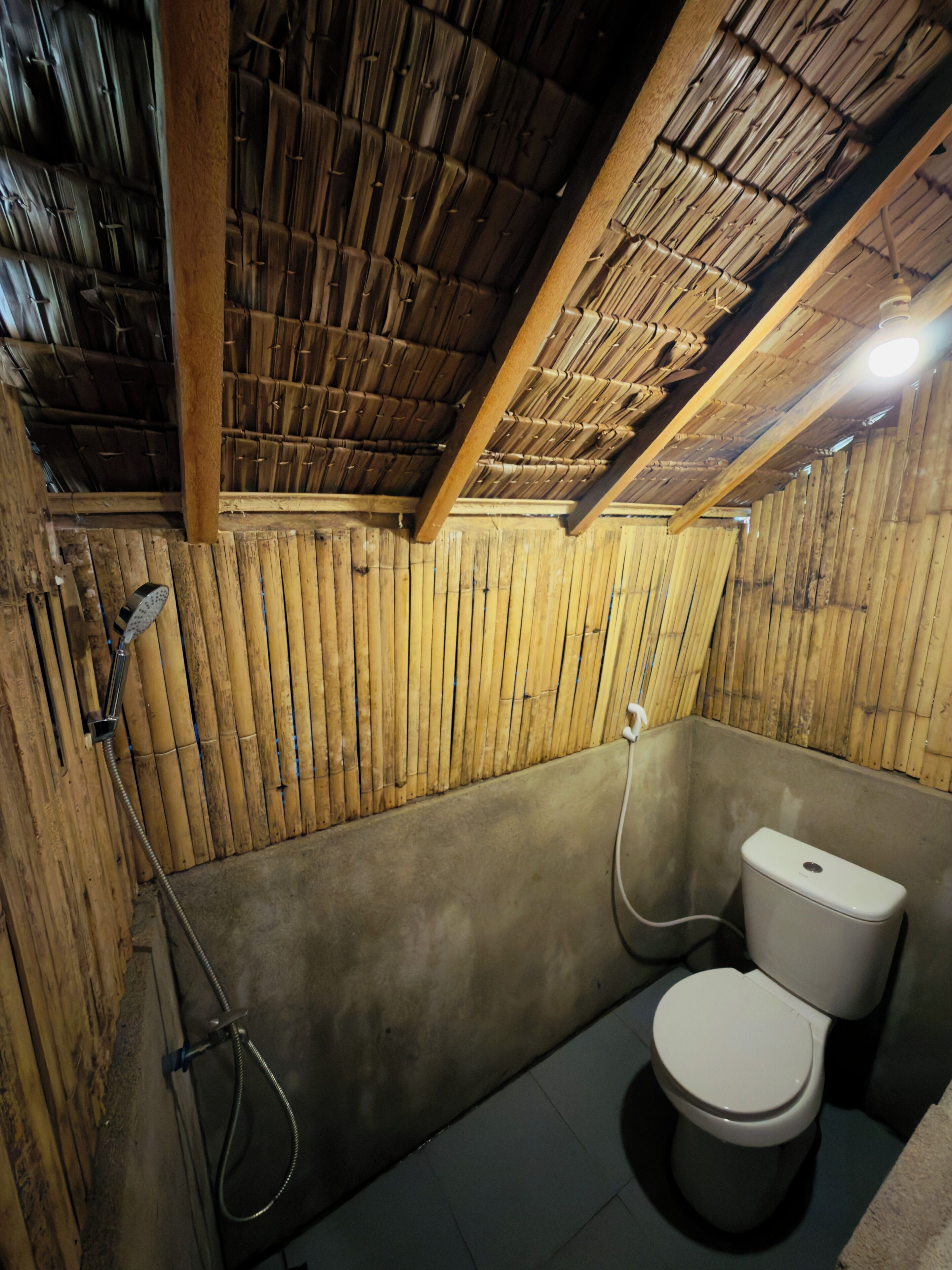 A bathroom with a bamboo ceiling, a toilet, and a shower.