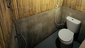 Ein Badezimmer mit Bambusdecke, Toilette und Dusche.