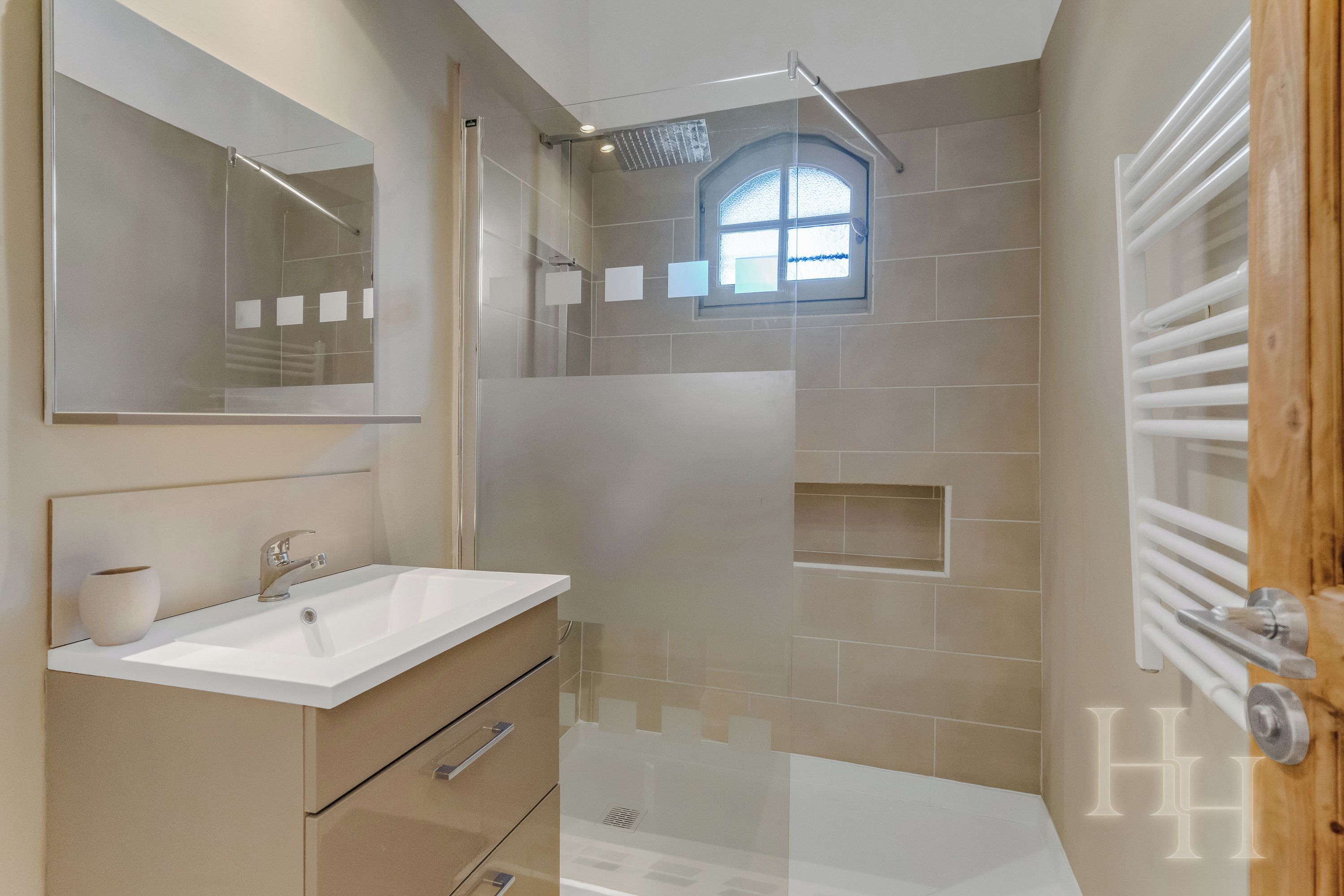 A bathroom with a bathtub, a shower, a vanity with a mirror, and a window.