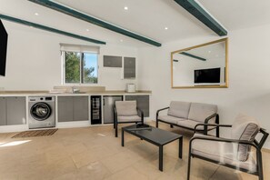 Eine moderne Küche mit eingebauten Geräten, einem Essbereich mit Tisch und Stühlen sowie einem großen Spiegel an der Wand.