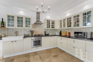 Eine moderne Küche mit weißen Schränken, einem eingebauten Backofen, einem Gasherd und einer Mikrowelle.