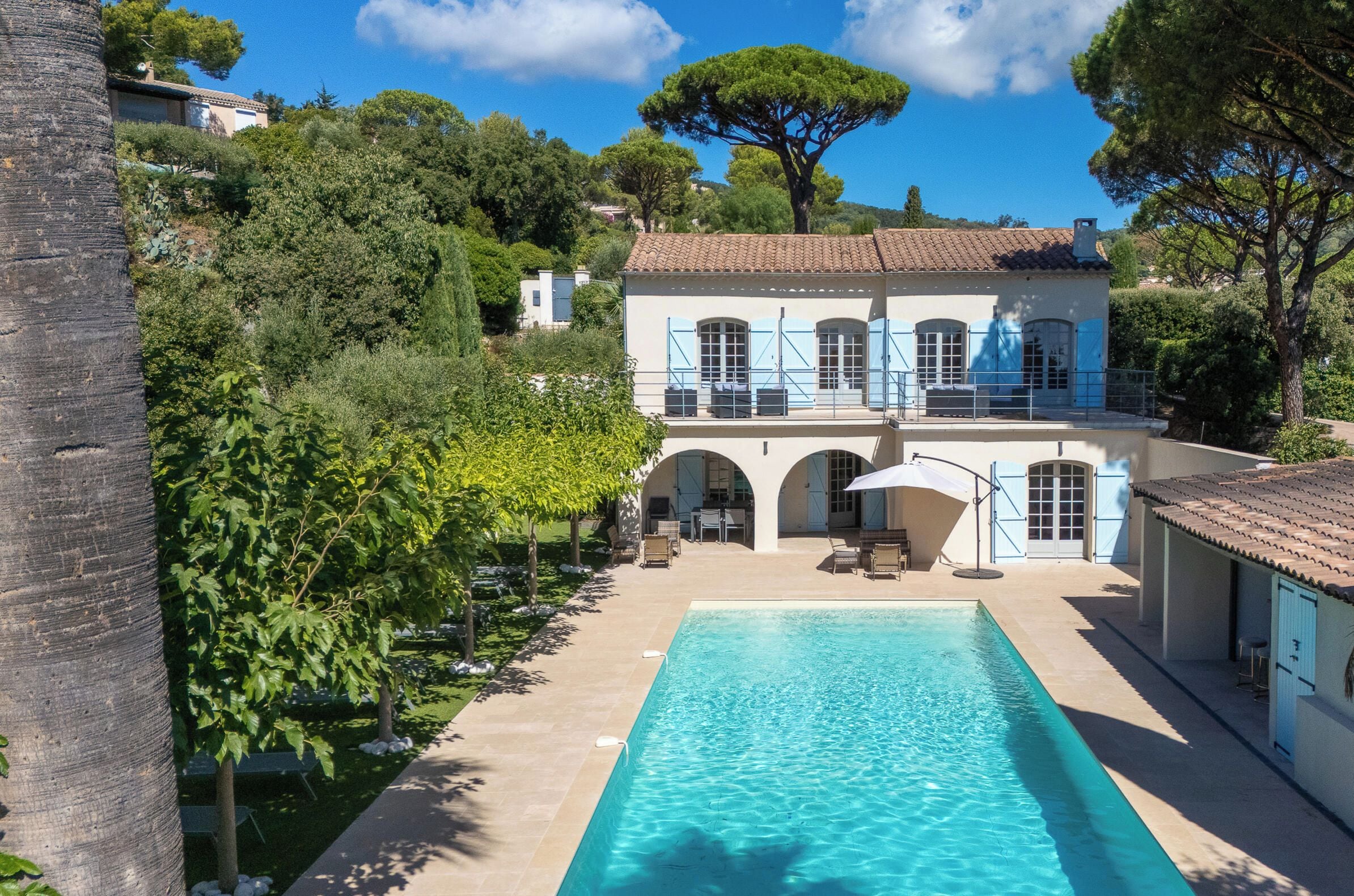 A villa with a swimming pool, outdoor seating, and a garden.