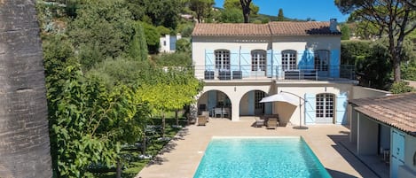 A villa with a swimming pool, outdoor seating, and a garden.