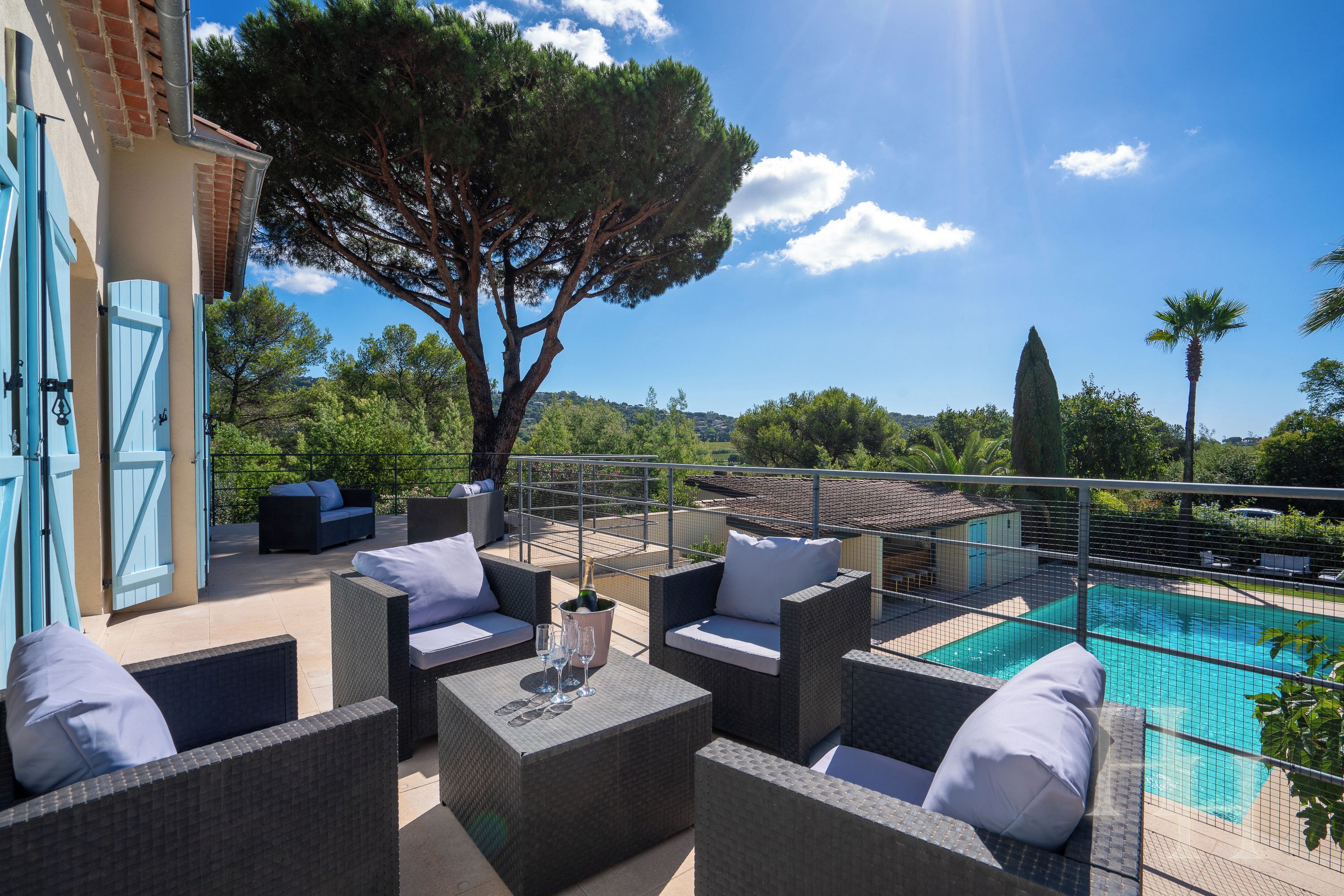 A rooftop terrace with outdoor furniture, a swimming pool, and a view of the surrounding landscape.