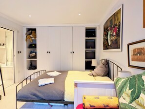 A bedroom with a bed, a wardrobe, a bedside table, a lamp, and a painting on the wall. - Cozy studio in a coolest London neighbourhood perfect for your stay (London)
