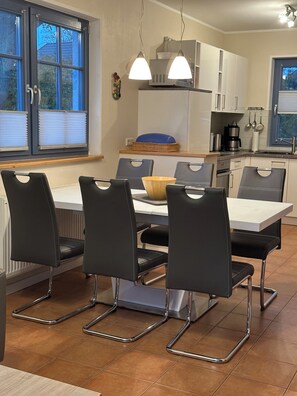 A modern kitchen with a dining area, featuring a table with chairs, a coffee machine, and a microwave. - "Sommerwind" townhouse with 95 square meters of living space and a large, quiet lot (fenced), close to downtown (Zingst)