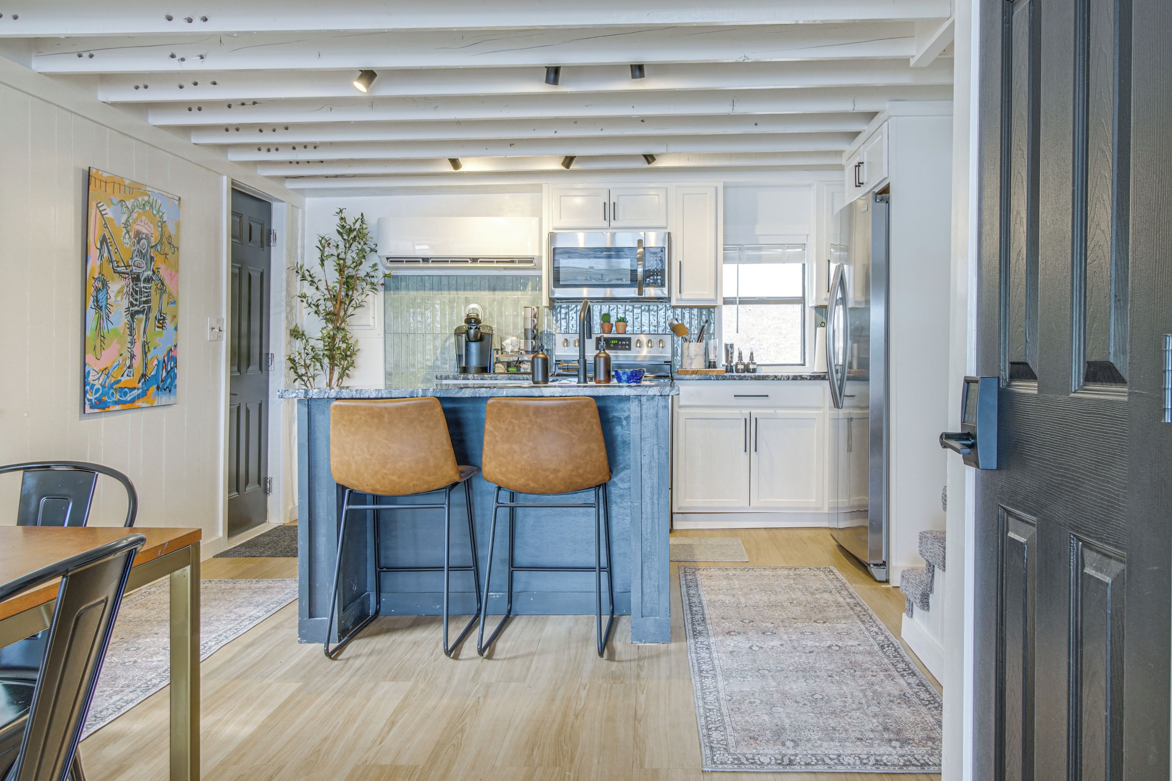 A modern kitchen with a central island, bar stools, and a dining area with a table and chairs.