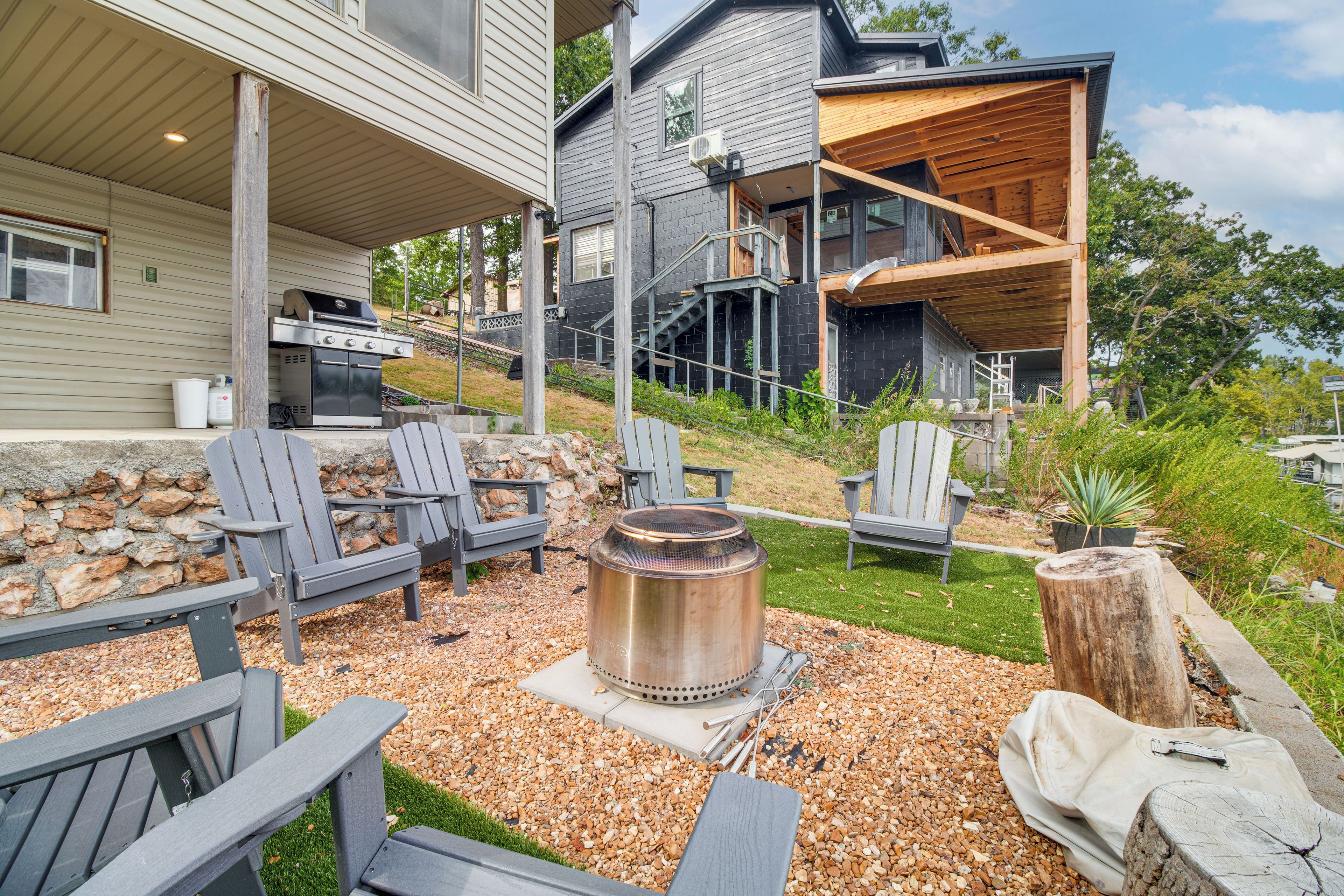 Ein moderner Außenbereich mit Terrasse, Grill, Sitzgelegenheit und Feuerstelle.