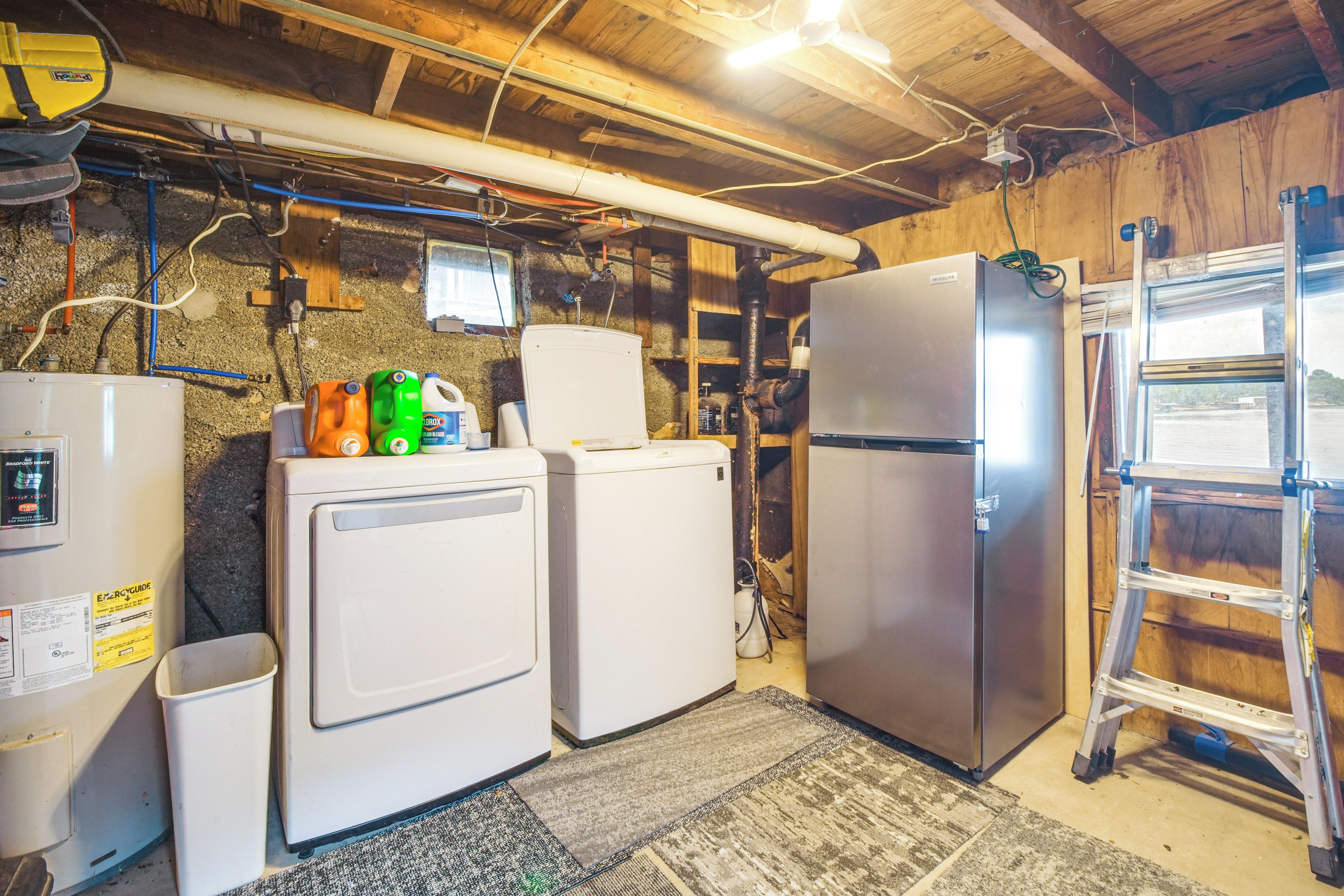 A laundry room with two white washing machines, a refrigerator, and a water heater.