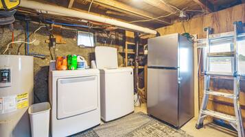 A laundry room with two white washing machines, a refrigerator, and a water heater.
