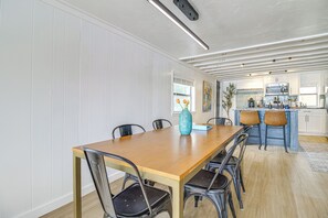 Ein Essbereich mit Holztisch und Stühlen, einer Vase mit Blumen und einer Küche im Hintergrund.