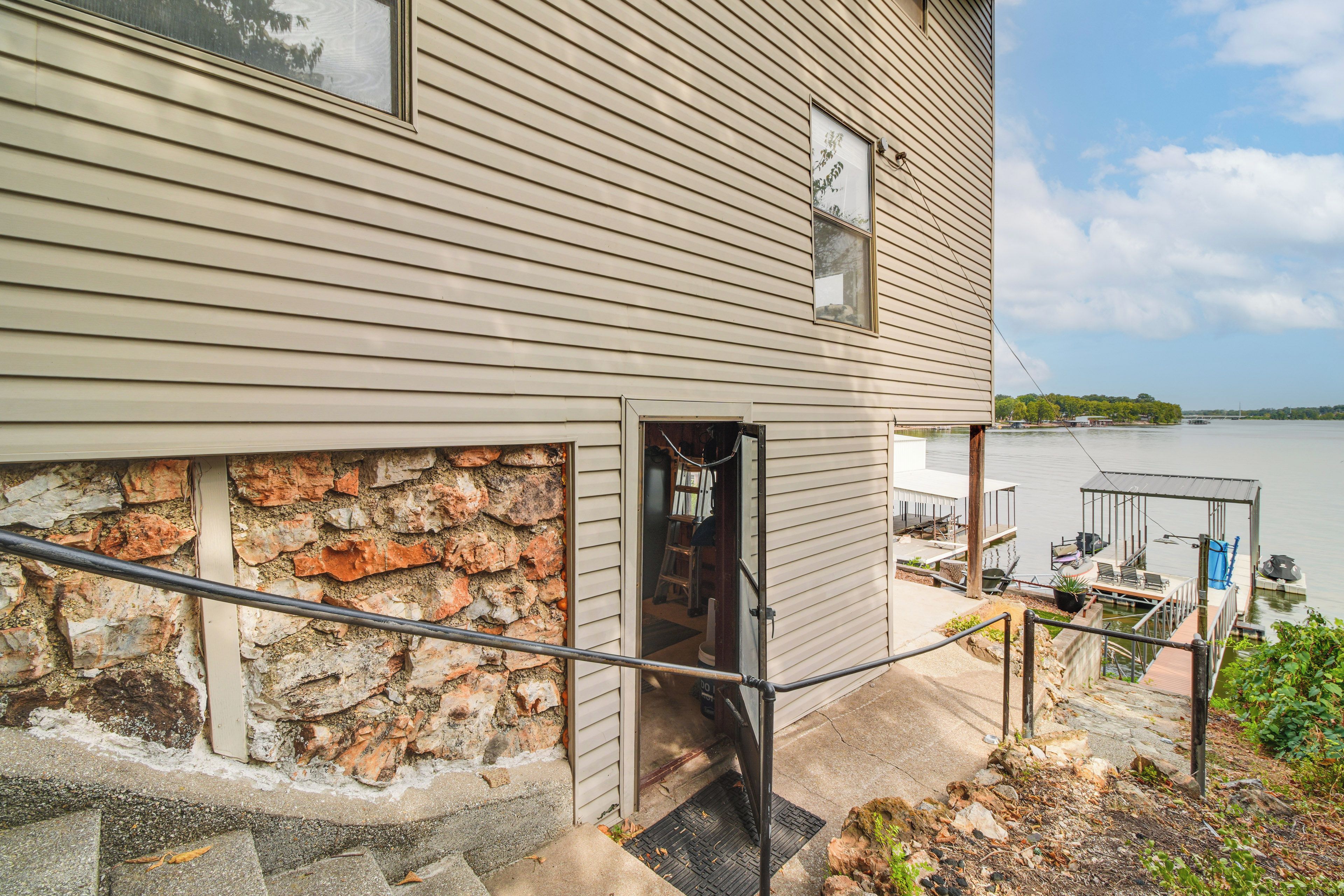 A house with a stone foundation, a wooden exterior, and a dock extending into a body of water.