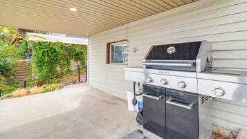 An outdoor kitchen with a grill, oven, and a window.
