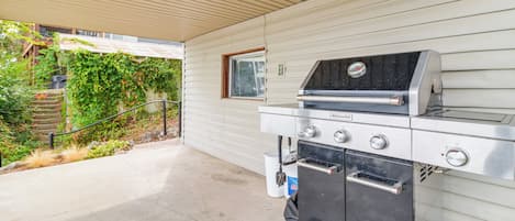 An outdoor kitchen with a grill, oven, and a window.