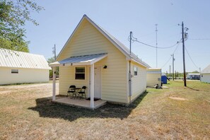 A small, single-story building with a pitched roof and a porch with two chairs. - Walk to Main Street! Cozy Stockdale Cabin (Stockdale)