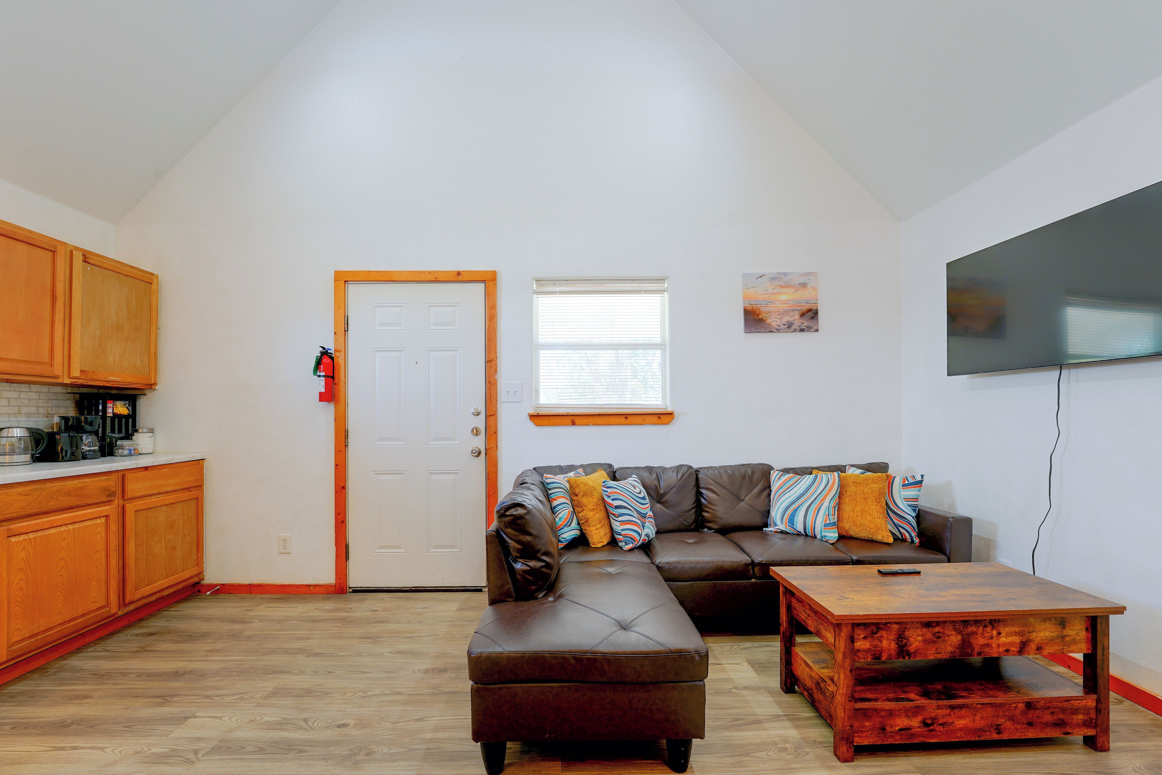 A compact living space with a kitchenette, a sofa set, a coffee table, and a television.