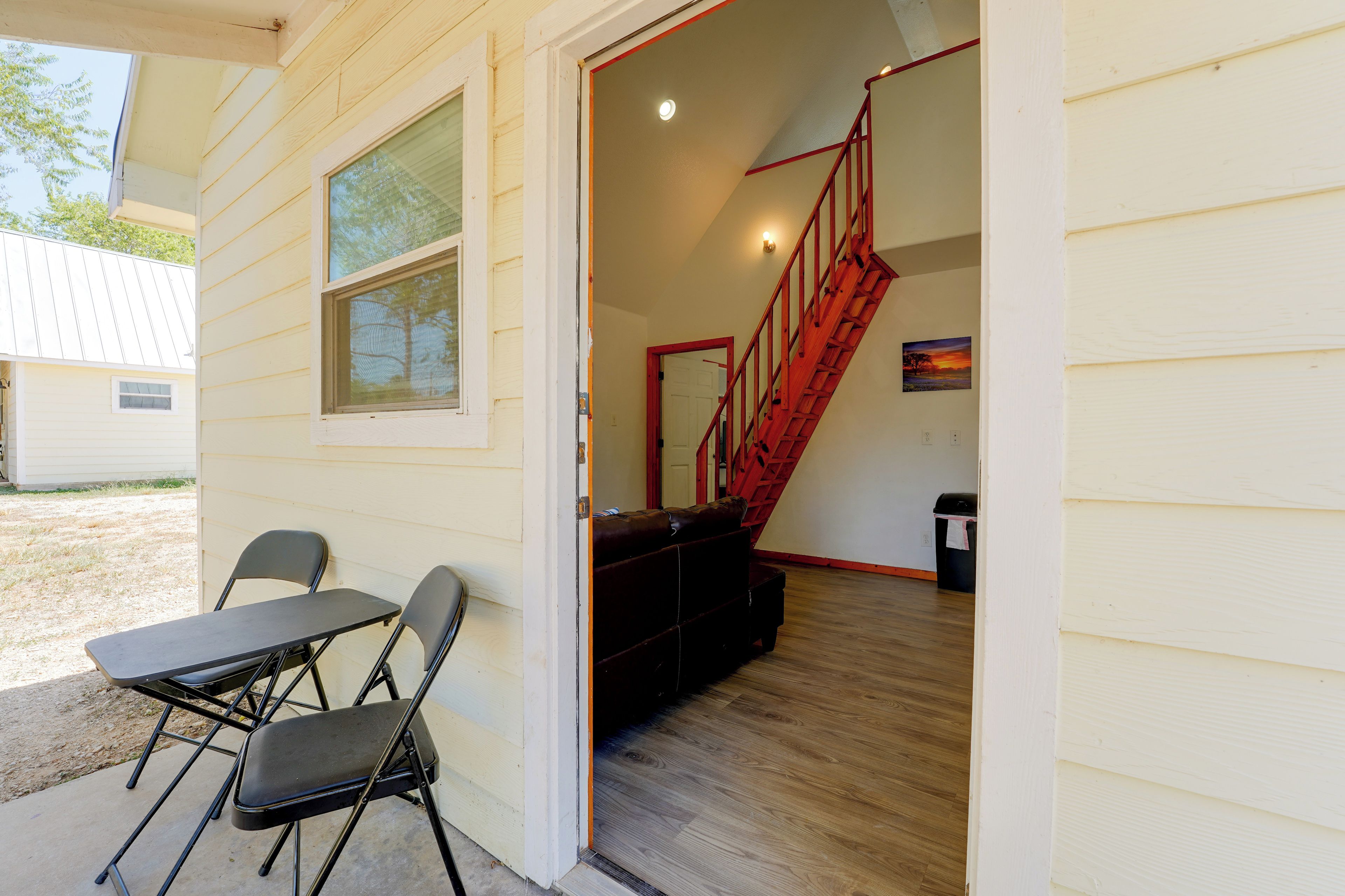 A room with a wooden floor, a red staircase, and a table with chairs.