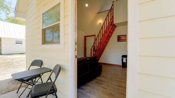 A room with a wooden floor, a red staircase, and a table with chairs.