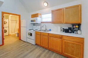 A compact kitchen with wooden cabinets, a built-in microwave, a stove, and a sink. - Walk to Main Street! Cozy Stockdale Cabin (Stockdale)