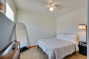 A bedroom with a bed, a bedside table, a lamp, a ceiling fan, and a mirror. - Walk to Main Street! Cozy Stockdale Cabin (Stockdale)
