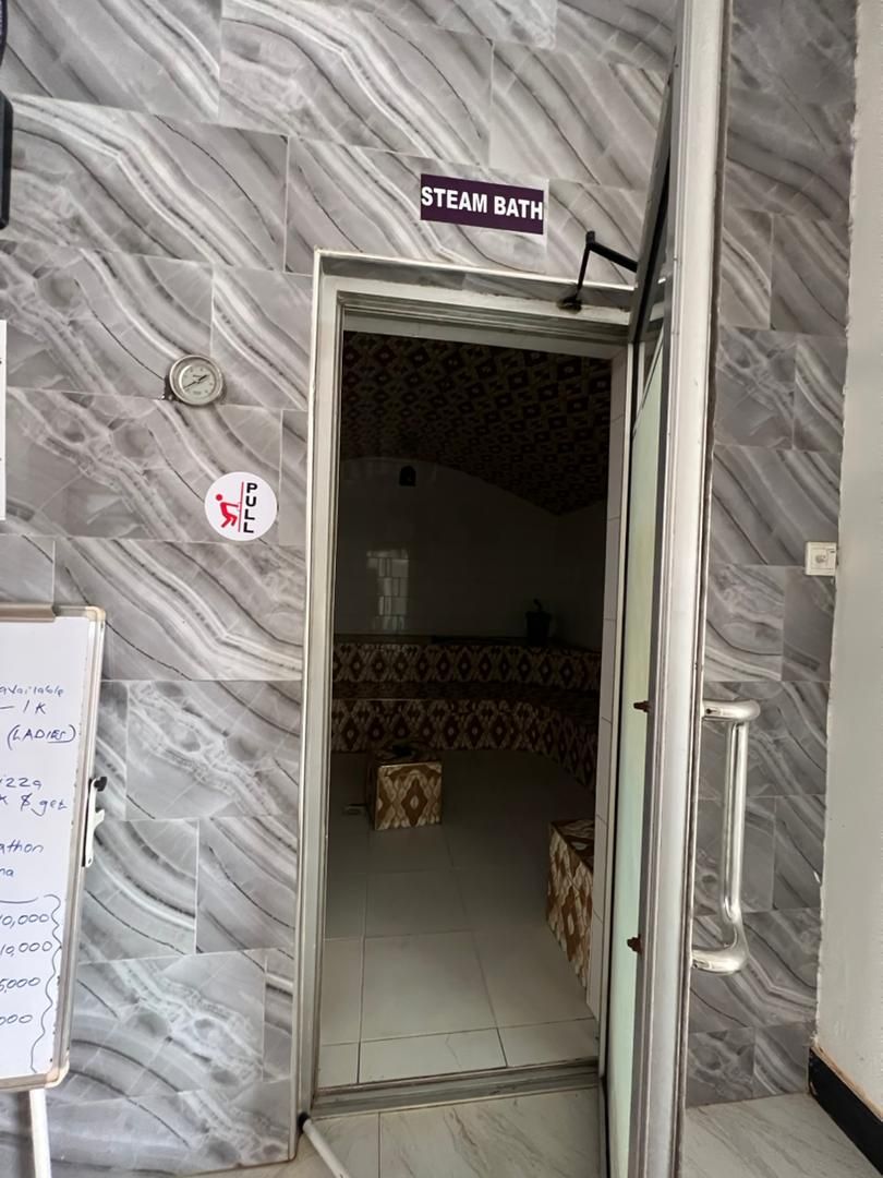 Un espace dédié aux bains de vapeur, avec une pancarte au-dessus de la porte, une barre de traction et un tableau blanc sur lequel on peut écrire.