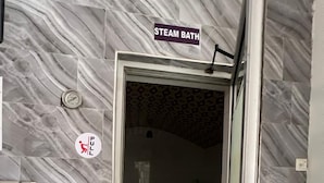 A steam bath area with a sign above the door, a pull-up bar, and a whiteboard with text.