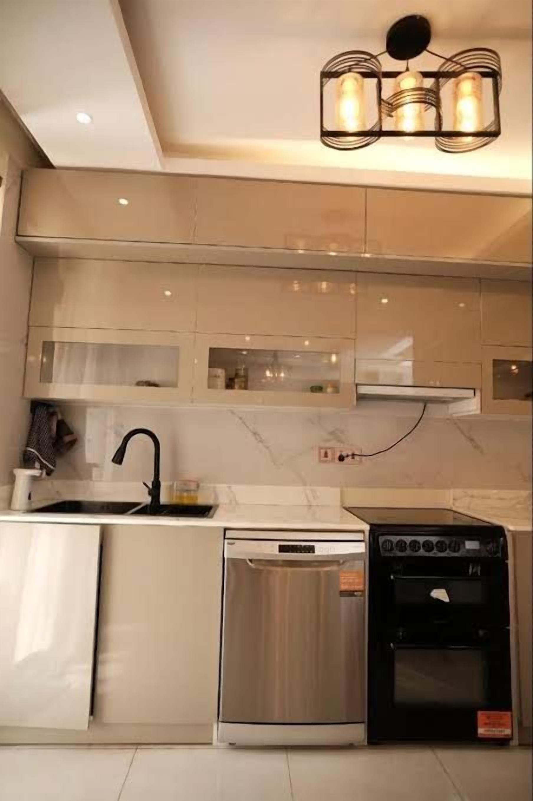 Une cuisine moderne équipée d’un lave-vaisselle, d’un four et d’un luminaire suspendu.